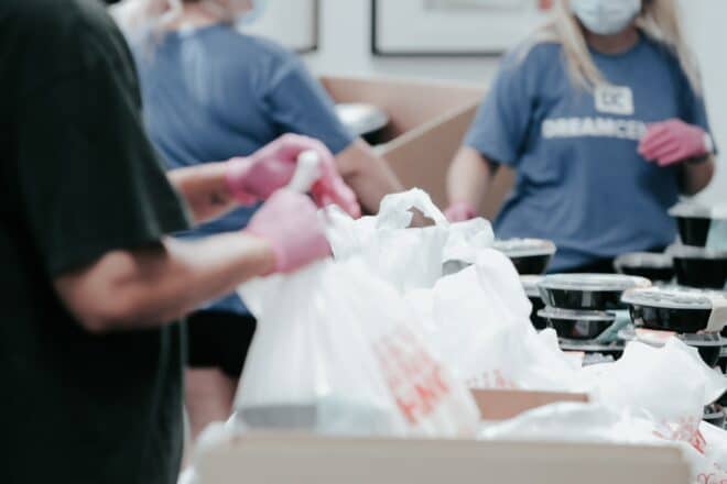 Voluntários trabalhando com sacolas de alimentos em local desconhecido